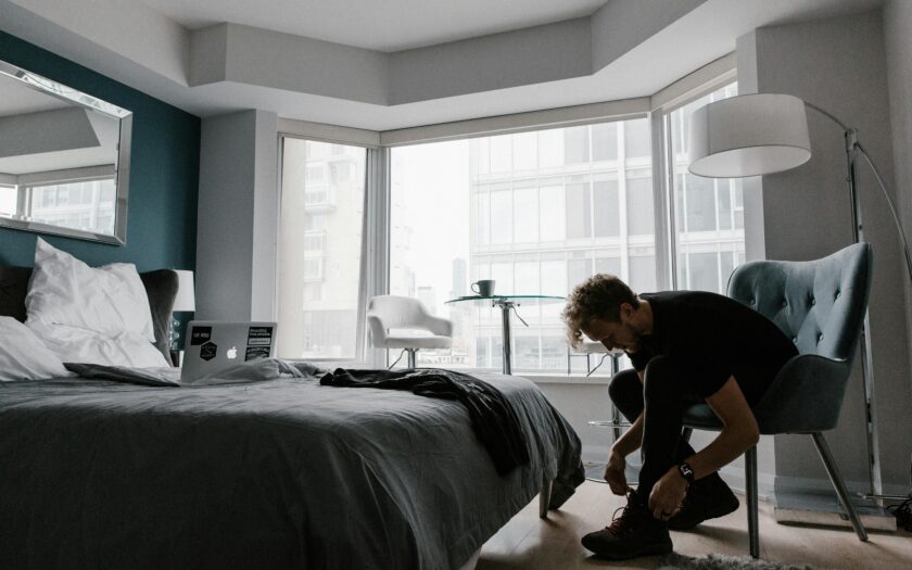 Contemporary hotel room with a man tying shoes in a bright Toronto setting.