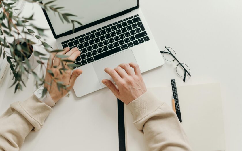 An overhead view of a person working on a laptop in a minimalist home office setting.